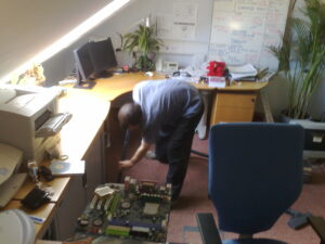 Gareth sucks water out from under a desk using a vacuum cleaner, #1.