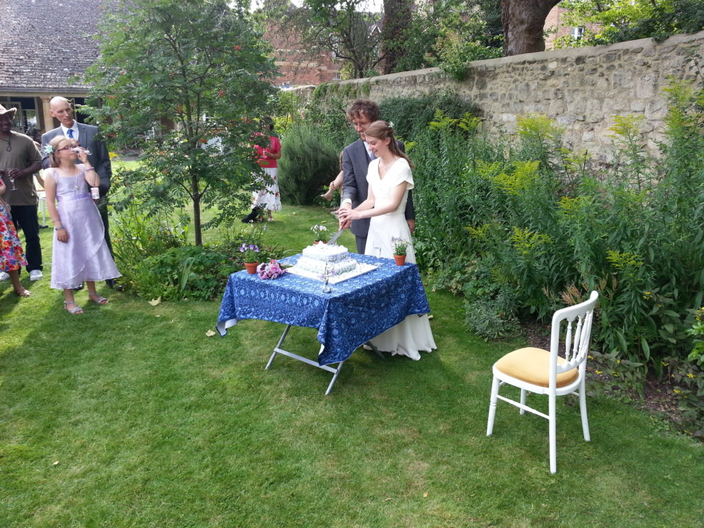Matthew and Katherine cut the cake in the garden of the Quaker Meeting House.