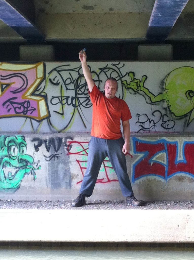 Dan holding the geocache he's found above his head, triumphantly.