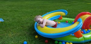 John flops over the side of the paddling pool.