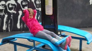 A girl does sit-ups in an outdoor gym.