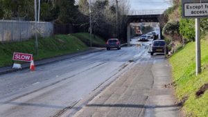 Floods under a railway bridge with cars fording the gap.