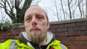 Dan, wet, by a brick wall