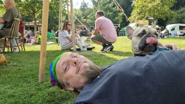Dan on grass with a dog; the dog's tongue is sticking out.