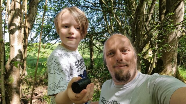 Dan crouches alongside an 8-year-old boy in a forest.