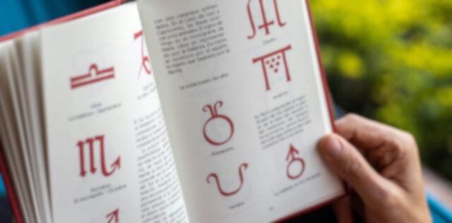 Book, held open, showing astrological symbols.