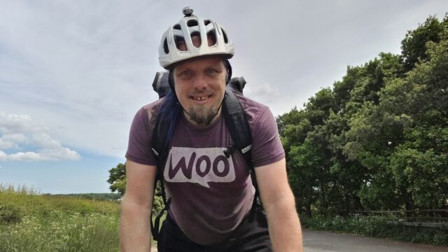 Leaning hard into his handlebars, Dan cycles up to the top of a rural hill.