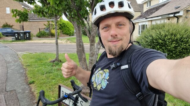 Dan, with his bike, throws a thumbs-up sign.
