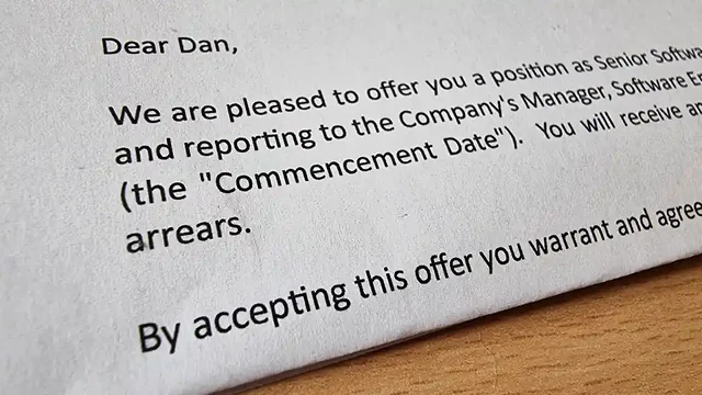 Close-up of part of a letter, the visible part of which reads: Dear Dan, We are pleased to offer you a position as Senior Softwa... / and reporting to the Company's Manager, Software E... / (the "Commencement Date"). You will receive an... / By accepting this offer you warrant and agree...
