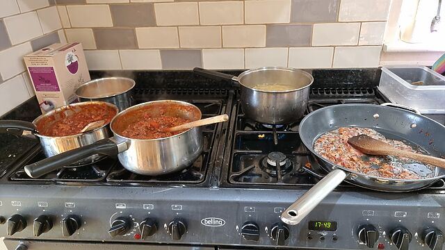 Eight-hob gas range with four saucepans and a large frying pan vein heated.