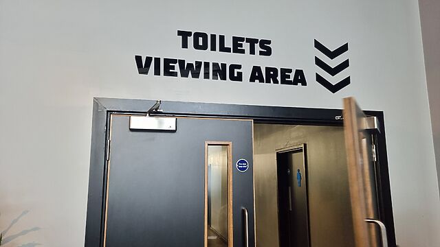 Sign above a door saying 'toilets' and 'viewing area' on separate lines, but looking slightly like they might be a single sentence.