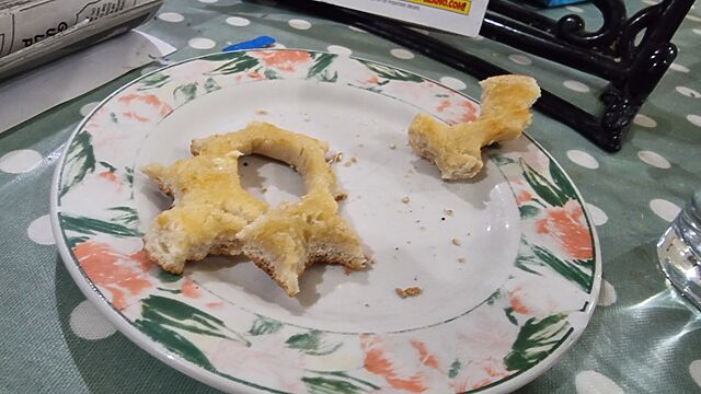 On a plate, buttered bagel has been nibbled all around the outside, leaving only the hole surrounded in a thin circle of bread.