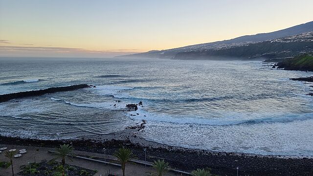 View of waves crashing into a bay on a rugged island coastline.
