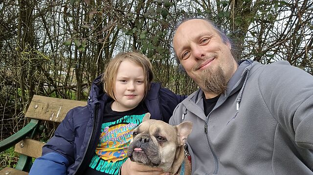 Dan sits with a young boy and a French Bulldog.