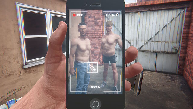 Screenshot from Hard Lads. Through the screen of a phone camera recording a video, we see two partially-dressed young men in the yard of a terraced house, alongside a folding chair.