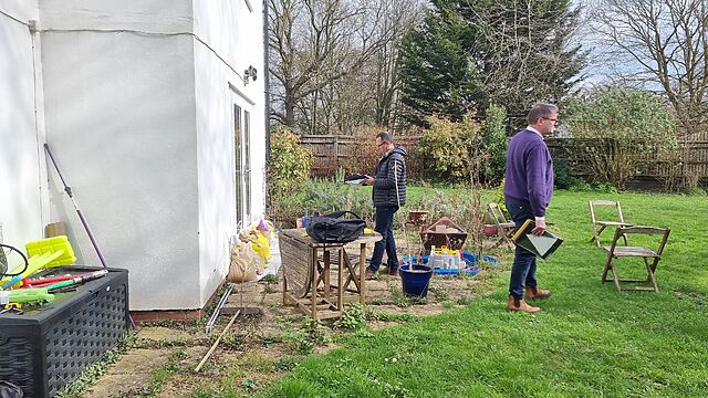 Two white men look at the outside of a sandbag-protected house.