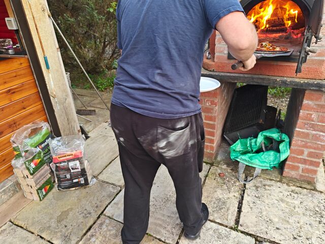 Close-up of Dan's butt, with a large white floury handprint on it, as he operates a pizza oven.