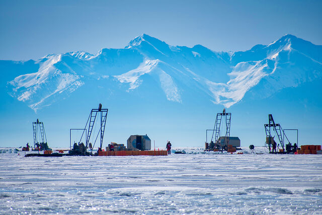 Scientists work around cranes atop a frozen lake.