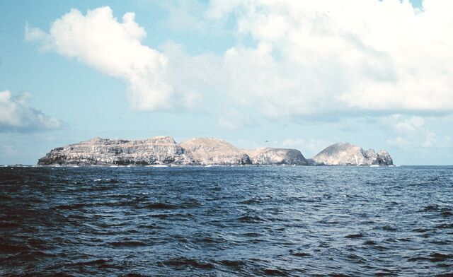 A rocky island protudes from the waves.