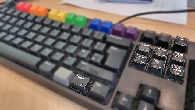 Close-up of a WASD keyboard with Pride rainbow keycaps, focussing on its Menu/Fn key and the handful of media keys it supports (which are primarily the Pause, Insert, Home, Delete, End, Page Up and Page Down keys).