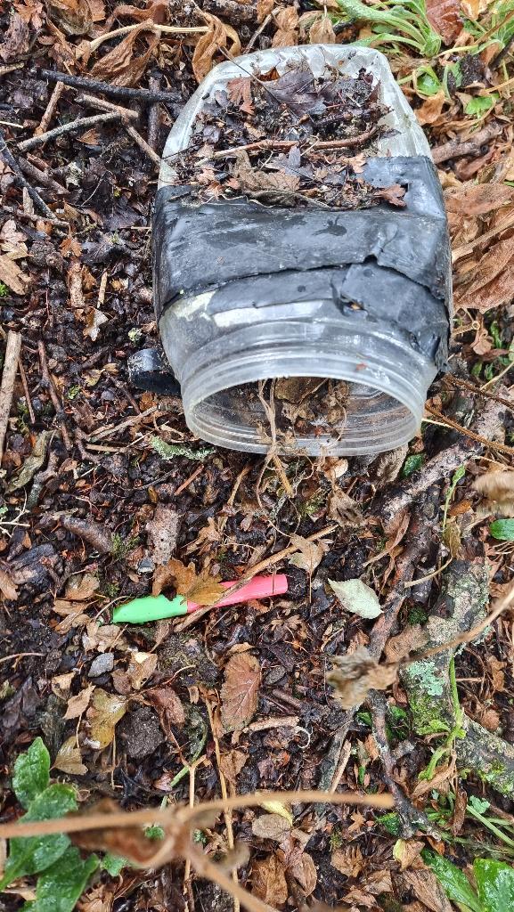 A badly damaged geocache with a toy whistle falling out of it.