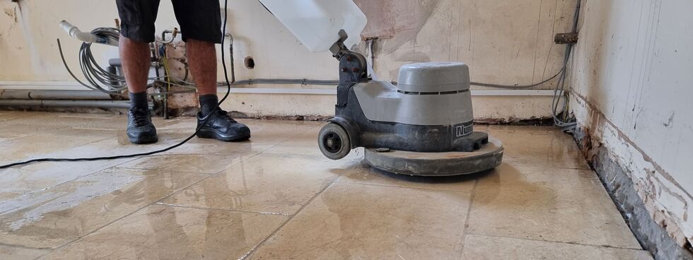 A floor-cleaning machine is pushed across a glistening limestone floor.