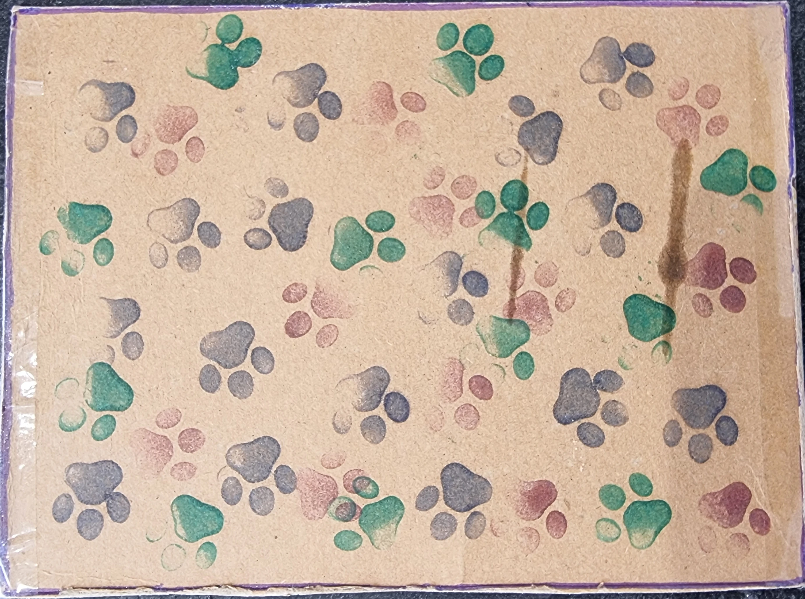 Plain brown card printed with a handmade green, blue and red dogprint pattern.
