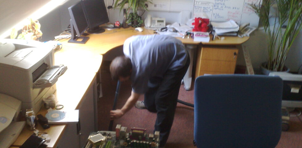 Gareth sucks water out from under a desk using a vacuum cleaner, #1.