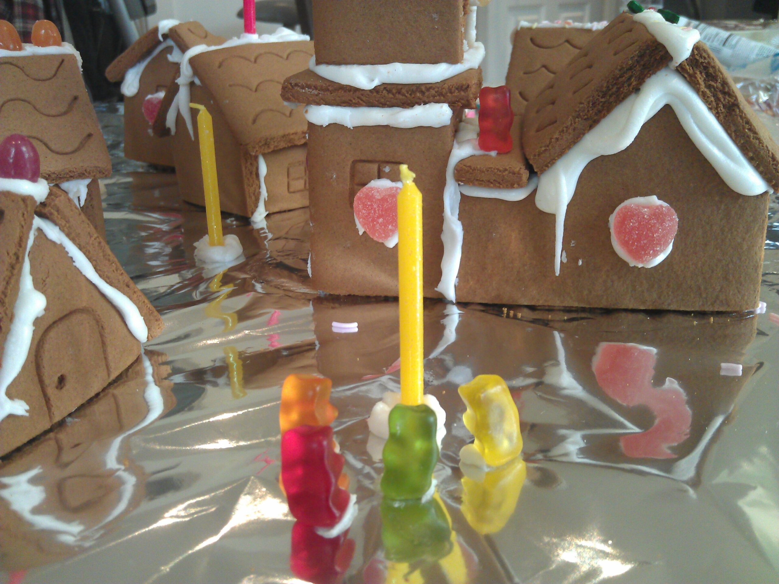 Full image of Gummy-bear citizens gather around a candle lamp-post in the gingerbread village. Little do they know of the horror that approaches...
