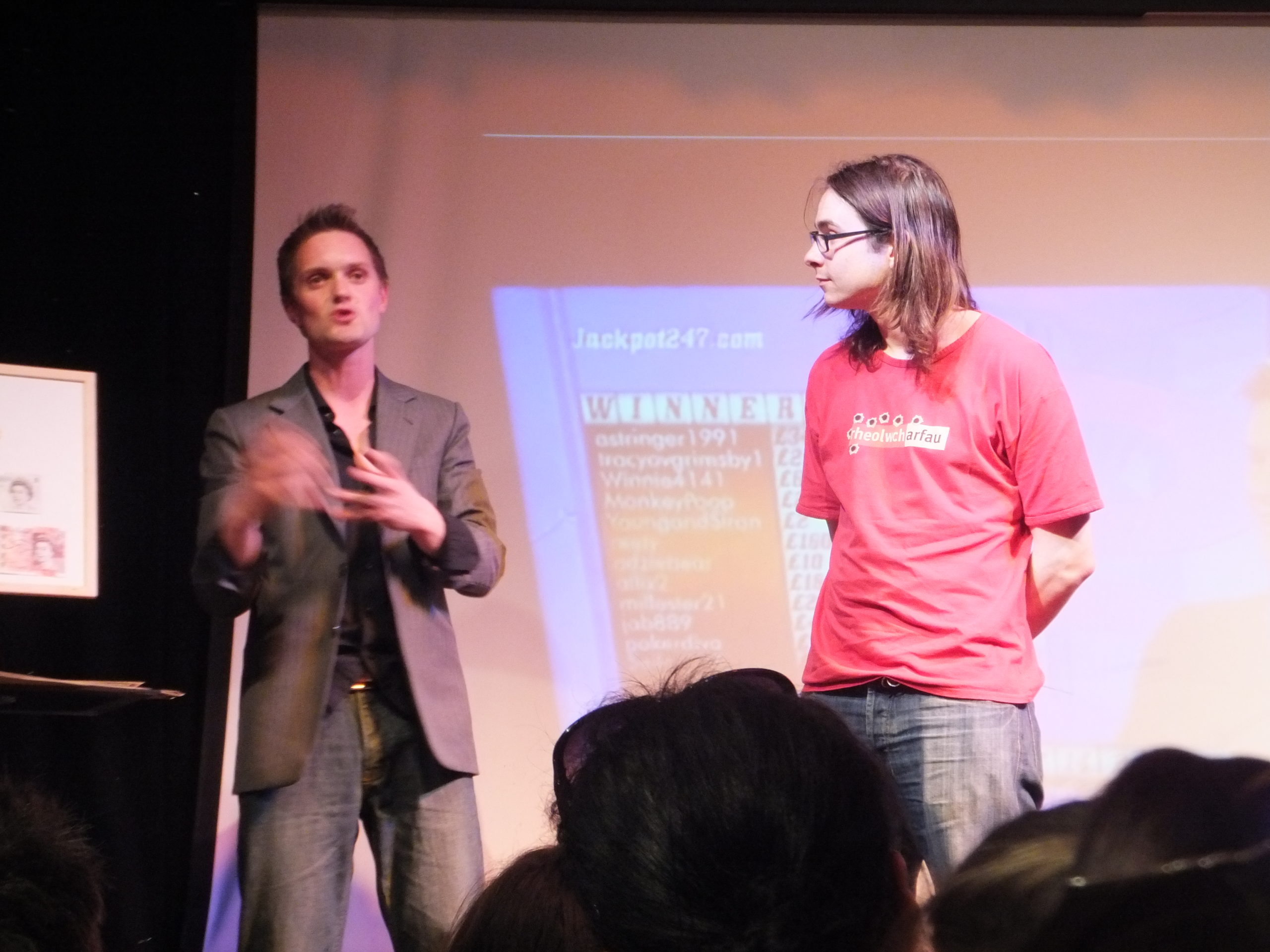 Full image of Matt R joins Sam Strange on stage to assist him with a magic trick.
