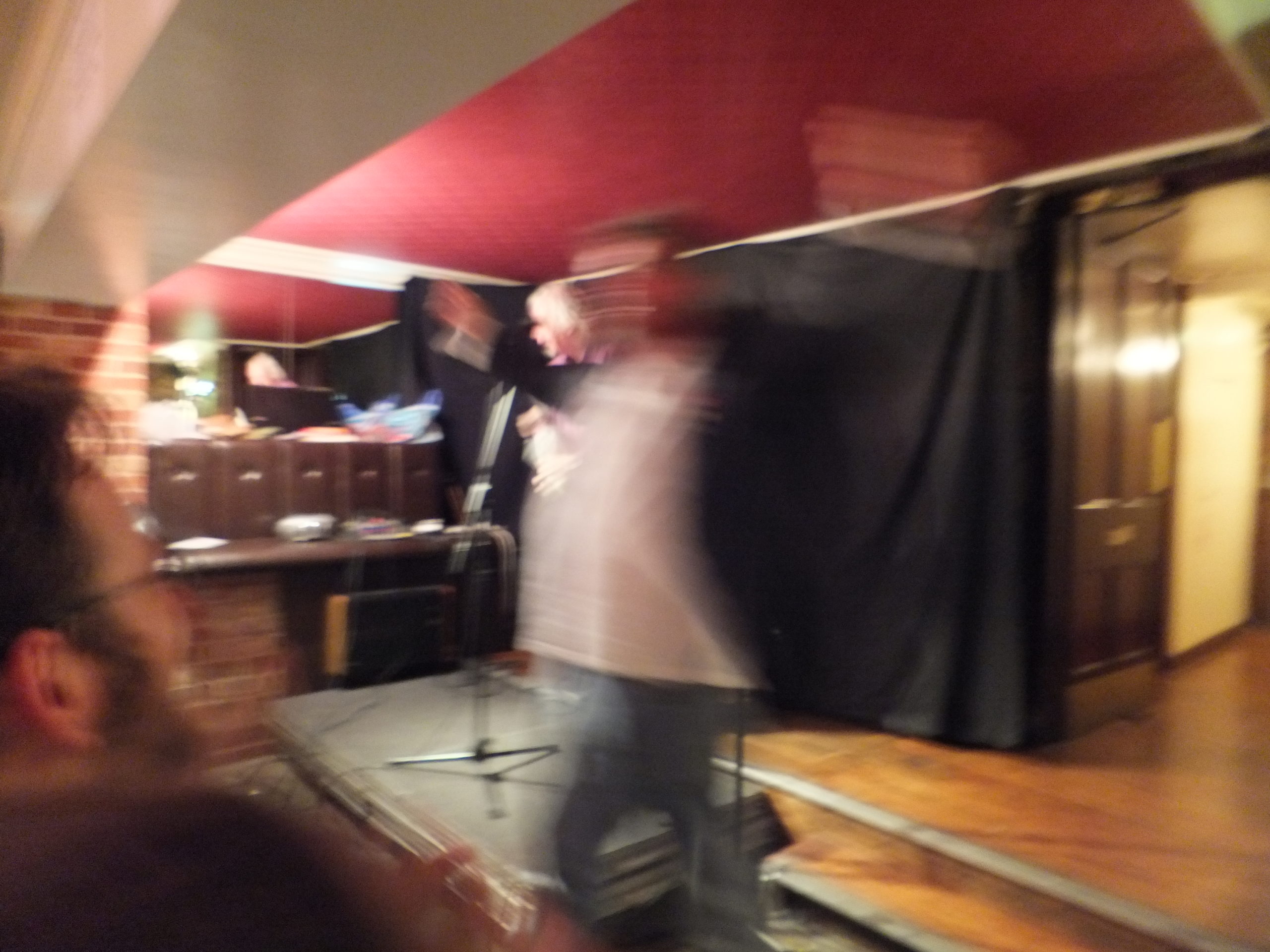 Full image of Phill Jupitus leaps around in front of JTA.