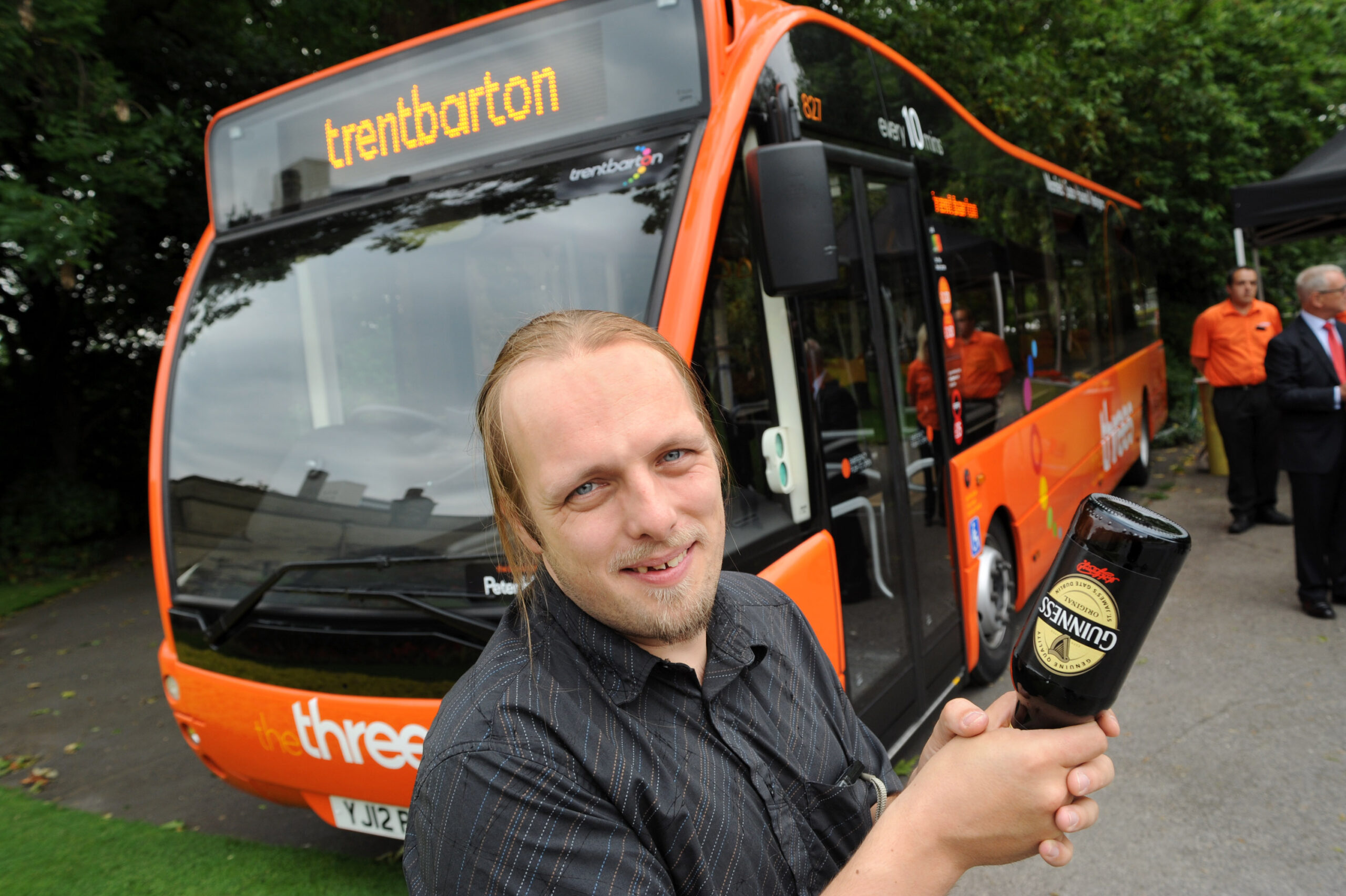 Full image of I hold a bottle of Guinness in preparation of "breaking" it over the front of the bus.
