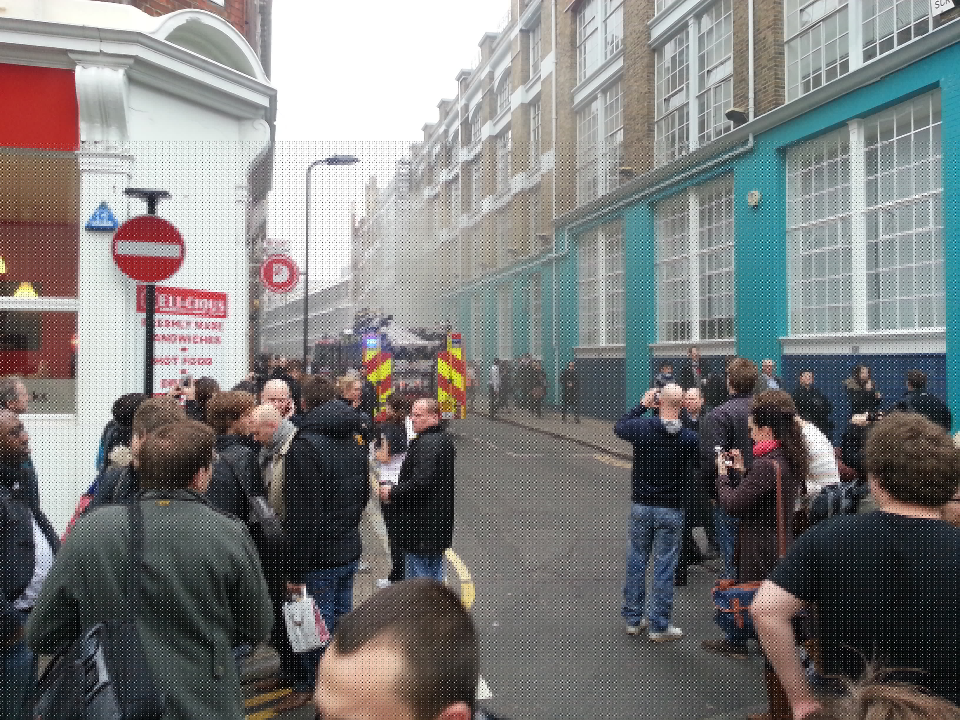 Full image of The first fire engines on the scene, as people are still filing out of the building.