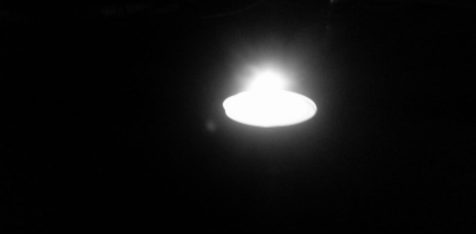 A tealight candle burning in the dark.
