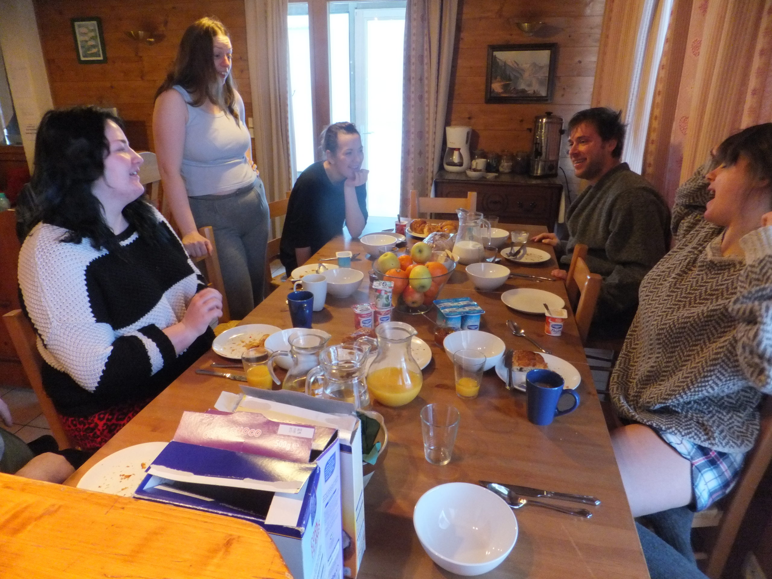 Full image of Ruth joins Becky, Harriet, Owen and Cat at the chalet's dining table.