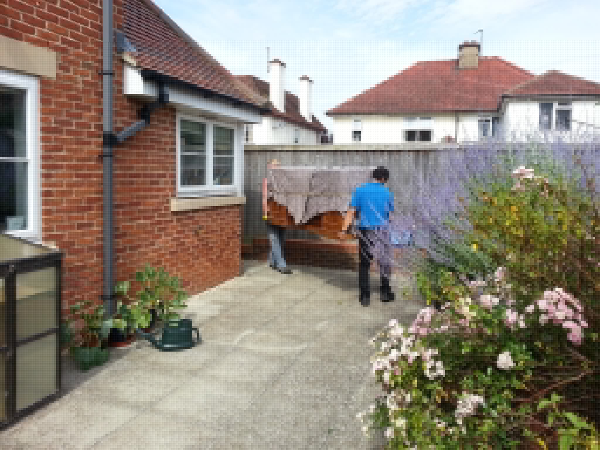 Full image of Removals men carry our sideboard out from the back door of New Earth.