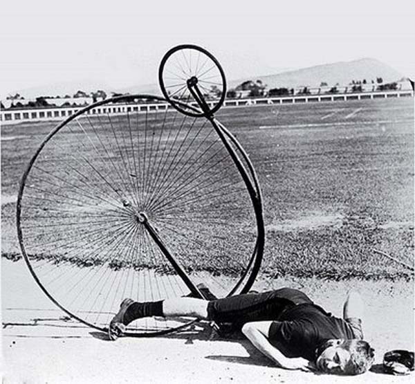 Full image of A penny farthing: the rider has tipped over the handlebars and ended up thoroughly upside-down.