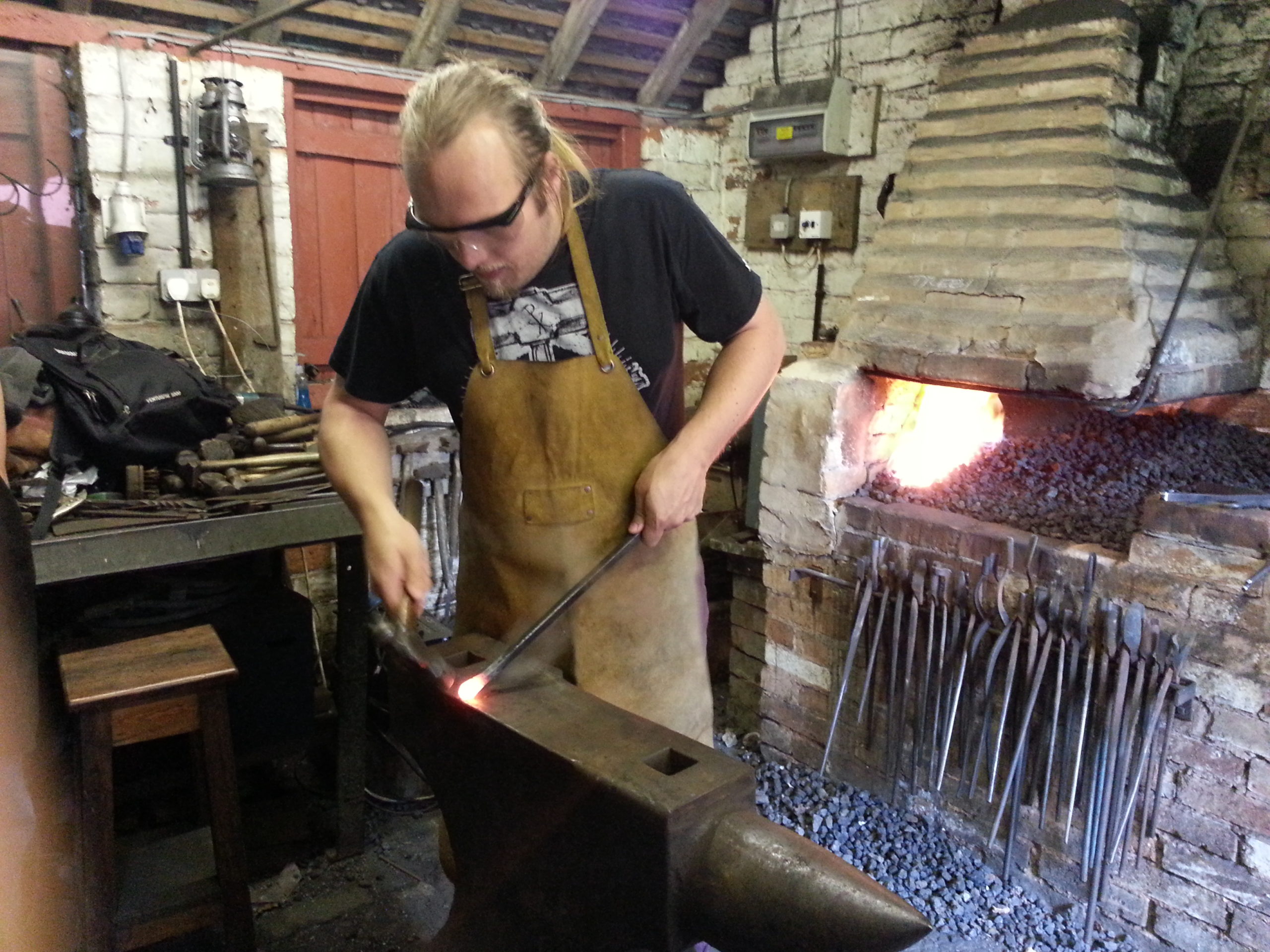 Full image of Dan hammers out a point on an anvil.
