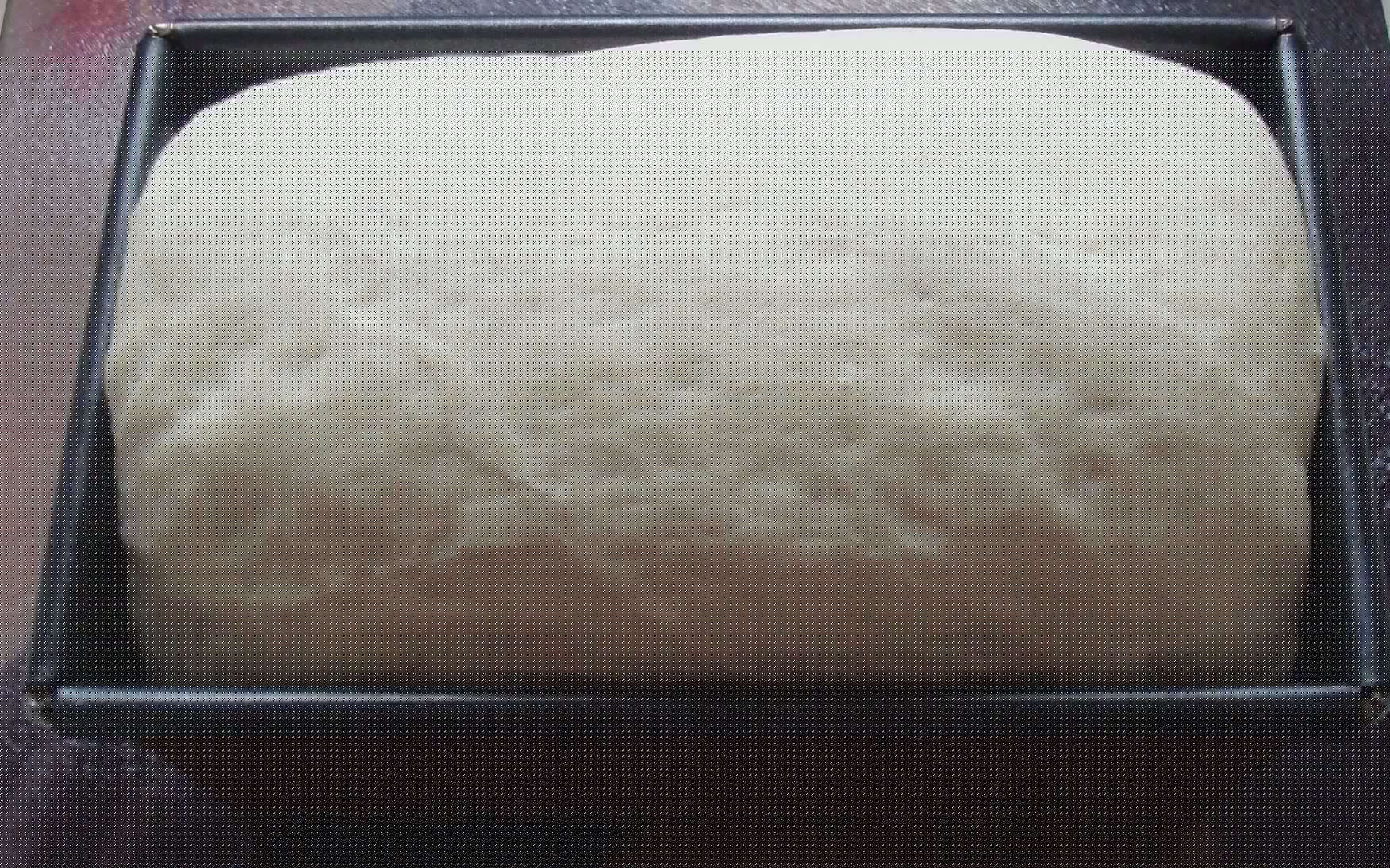 Full image of Bread dough in a loaf tin.