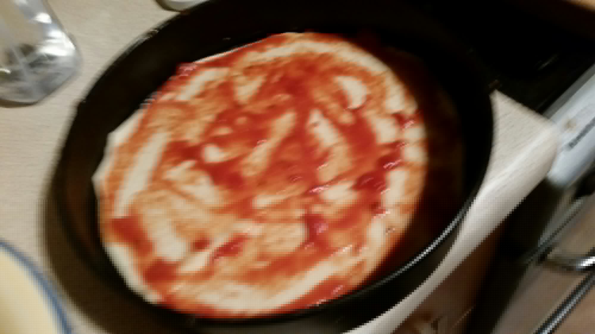 Full image of The first layer of pizza cake begins to be assembled in the tin.