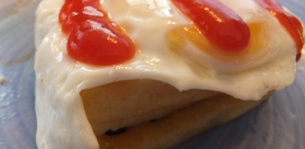 From bottom to top: potato waffle, cheese, potato waffle, egg, tomato ketchup.