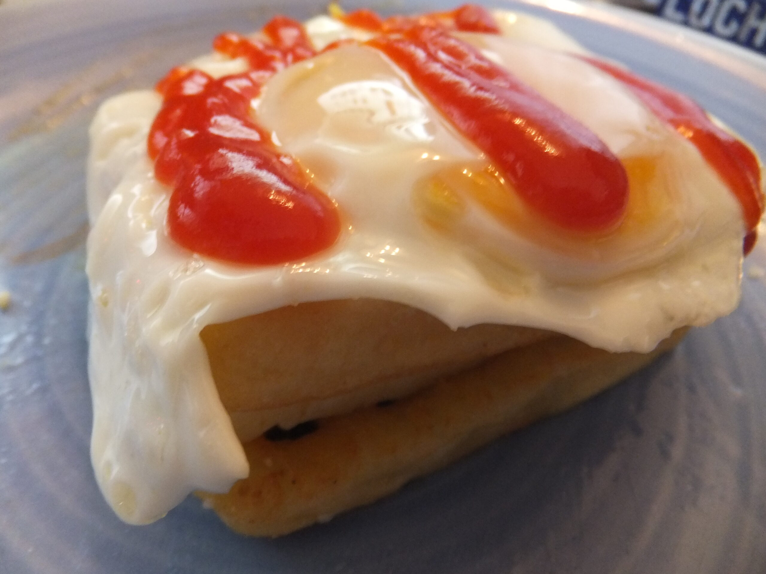 Full image of From bottom to top: potato waffle, cheese, potato waffle, egg, tomato ketchup.
