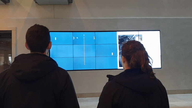 Two participants play Pong on the Heritage Window in Blackwell Hall at the Bodleian Library.