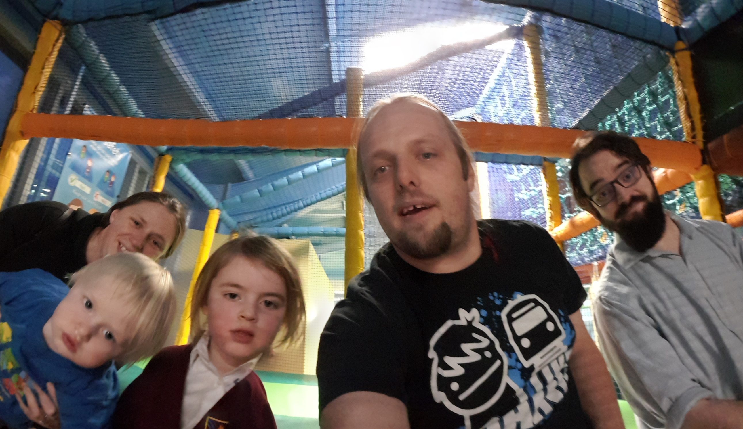 Full image of Ruth, Dan, JTA and the kids at the top of the slides at a soft play area.