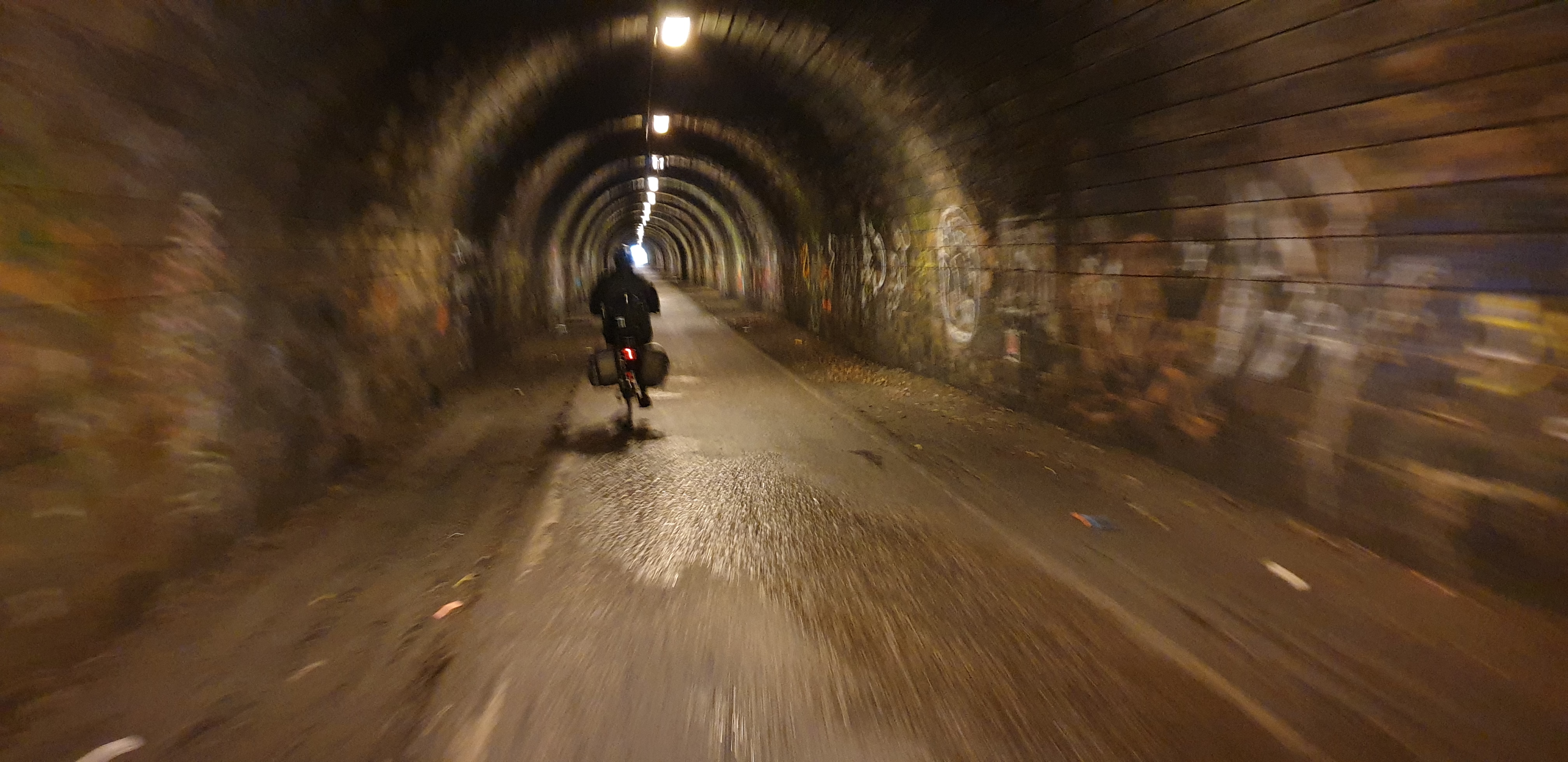 Full image of Ruth cycles through the former railway tunnel of The Innocent Railway.