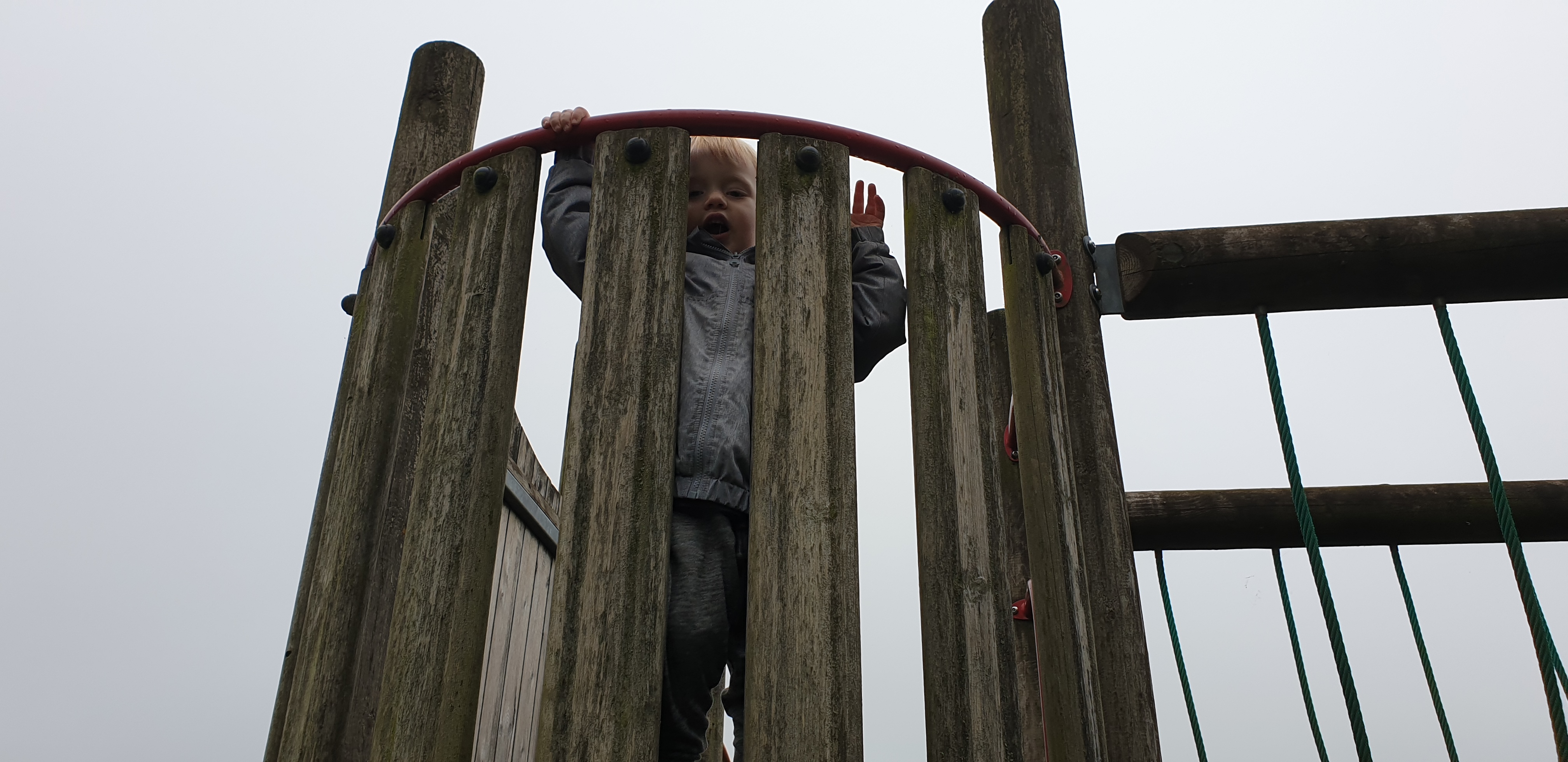 Full image of John looks down from the climbing frame.