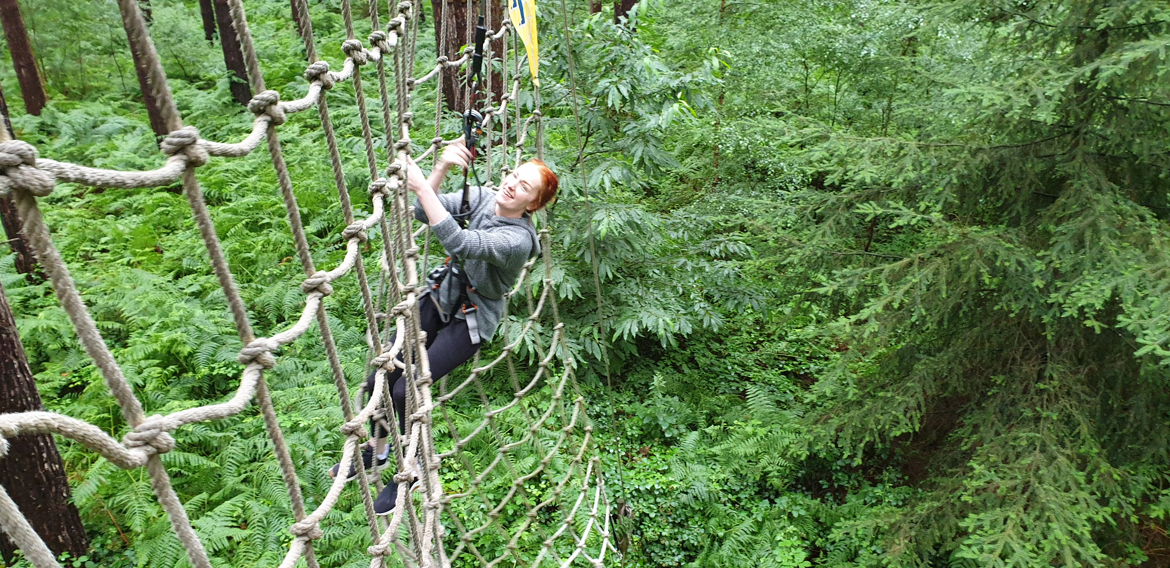 Full image of Sarah climbs the cargo netting after a tarzan swing.