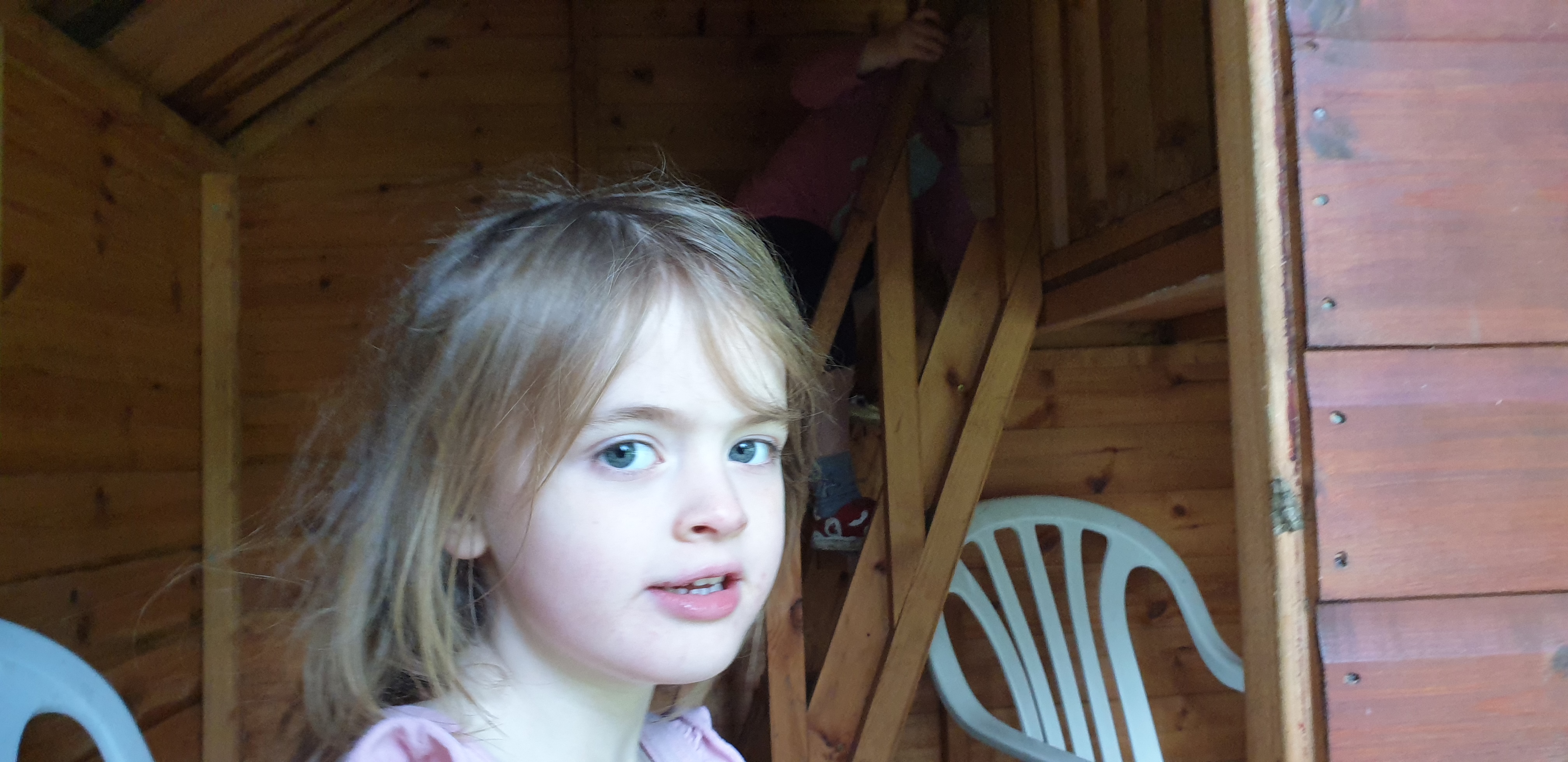 Full image of Annabel peeps out of her playhouse.