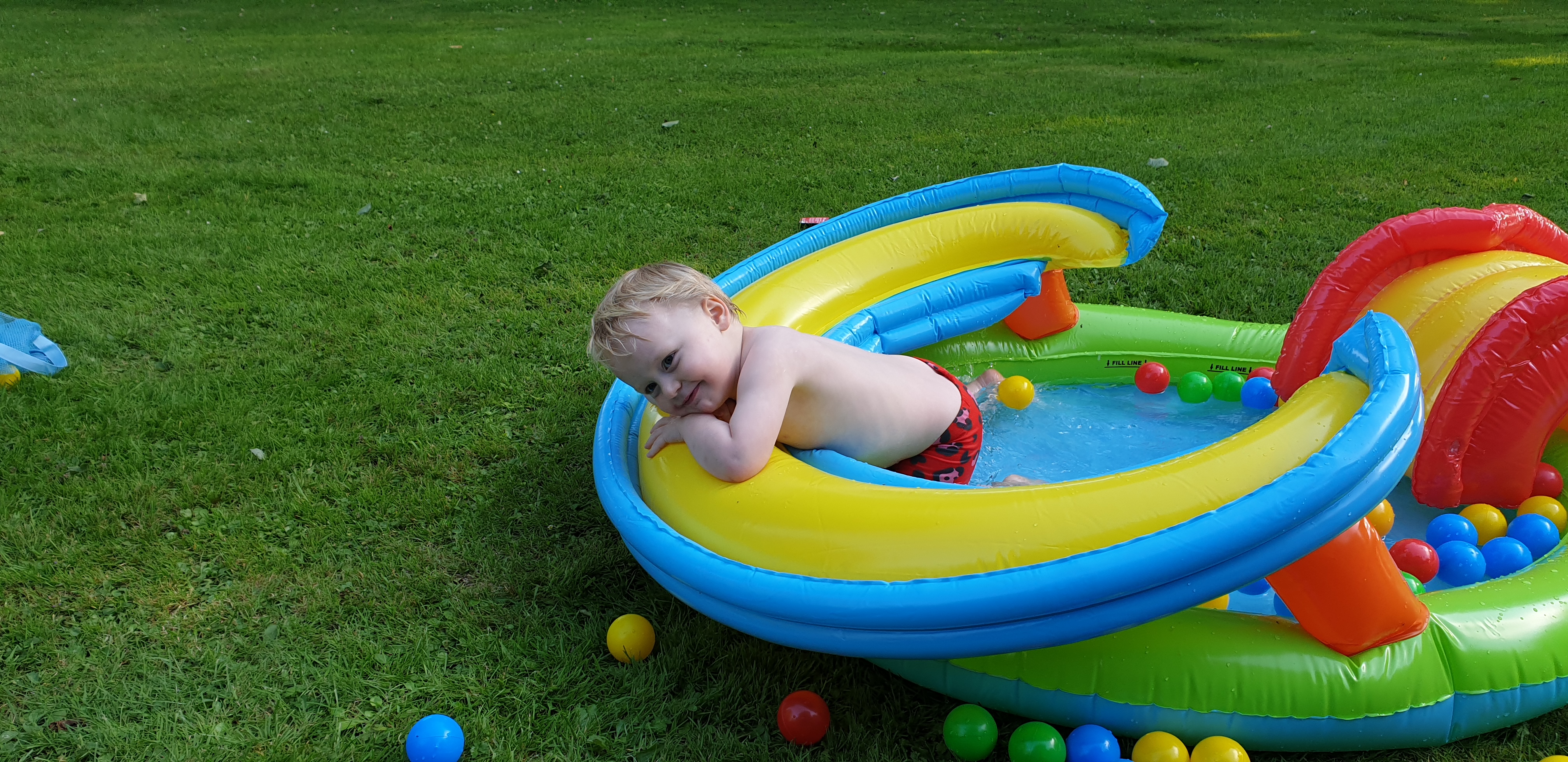 Full image of John flops over the side of the paddling pool.
