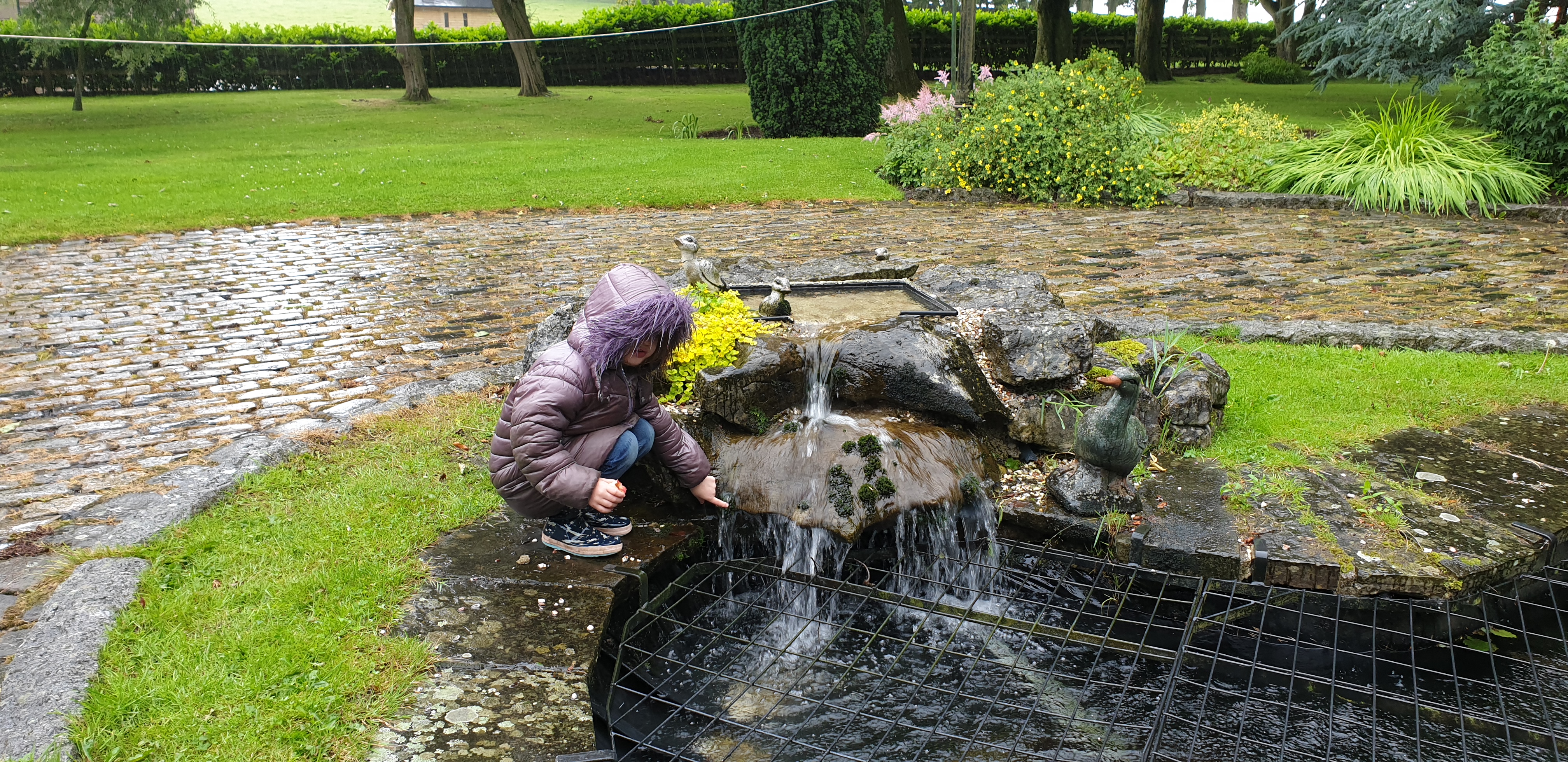 Full image of Annabel prods moss on the fountain.